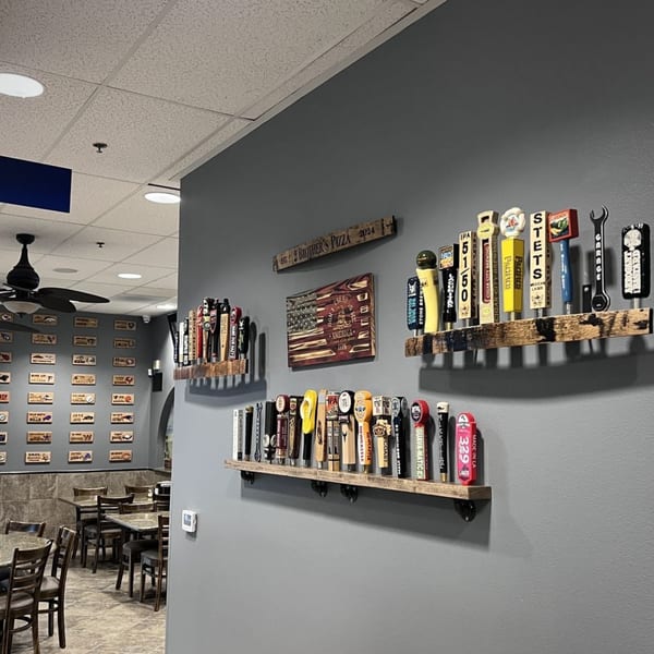 Interior of 2 Brother's Pizza, with beer tap handles displayed on gray walls and dining tables.