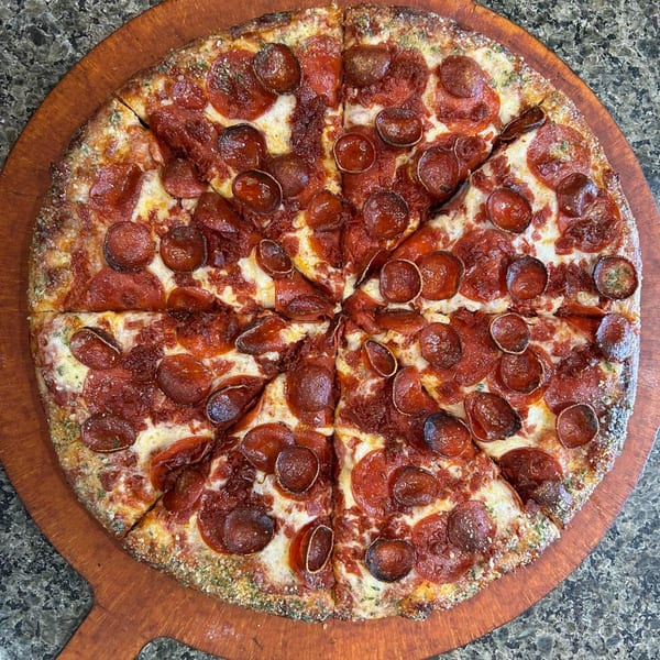 A whole pepperoni pizza from 2 Brother's Pizza, sliced into eight pieces on a wooden peel.