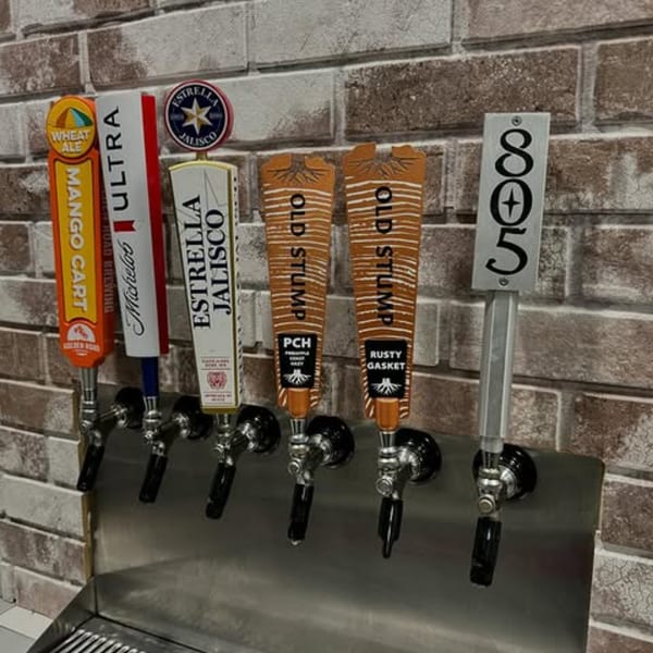 Six beer taps with various brand handles, including Mango Cart, Ultra, Estrella Jalisco, Old Stump, and 805.