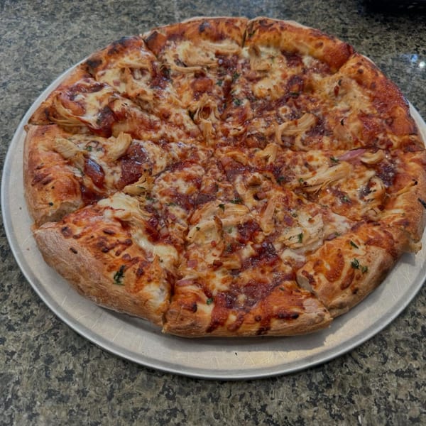 A whole BBQ chicken pizza from 2 Brother's Pizza, with a slice removed, on a metal tray.