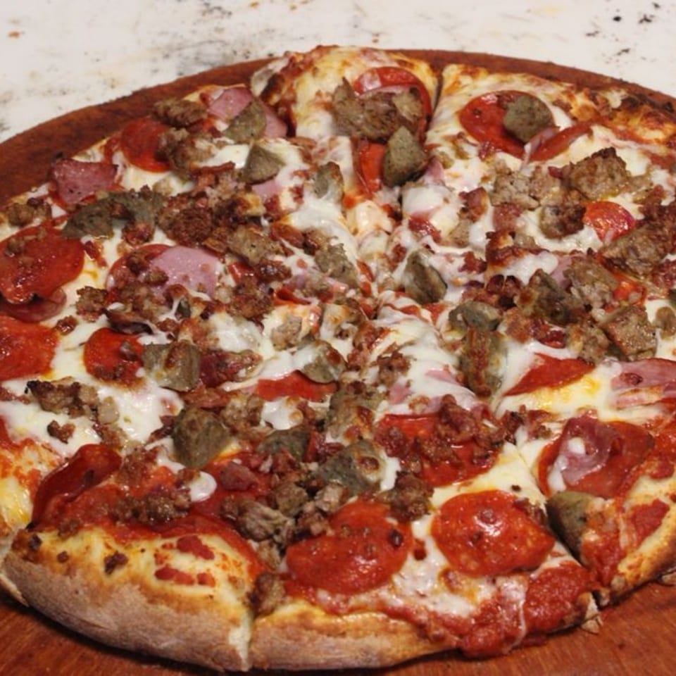 A whole meat lover's pizza from 2 Brother's Pizza, topped with pepperoni, sausage, and ham.